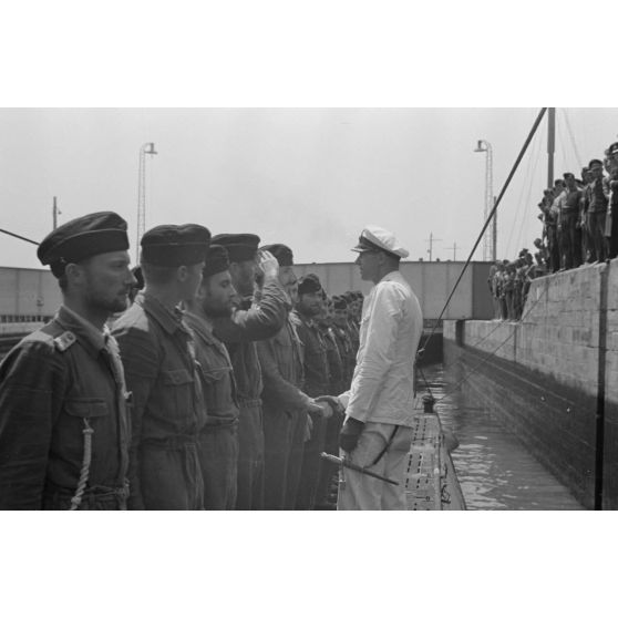 Sur le pont du sous-marin U-boot U-75, le capitaine (kapitänleutnant) Herbert Sohler, représentant de la 7.Unterseebootsflottille, passe en revue l'équipage.