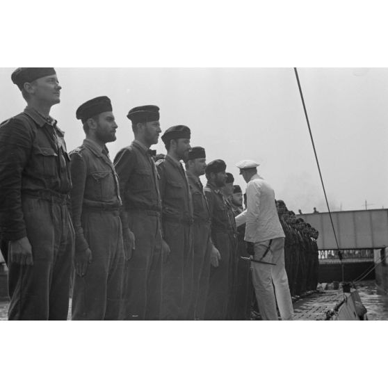 Sur le pont du sous-marin U-boot U-75, le capitaine (kapitänleutnant) Herbert Sohler, représentant de la 7.Unterseebootsflottille, passe en revue l'équipage.