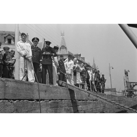 Lors du retour de croisière du sous-marin U-75, des marins, des aviateurs et des infirmières se pressent sur le quai du port de Saint-Nazaire.