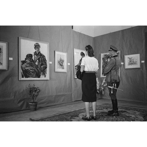 Une femme et un officier de la Wehrmacht visitent l'exposition consacrée aux peintures de Lothar-Günther Buchheim et de Richard Schreiber à l'hôtel Royal de La Baule.