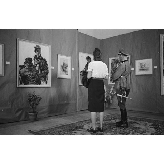 Une femme et un officier de la Wehrmacht visitent l'exposition consacrée aux peintures de Lothar-Günther Buchheim et de Richard Schreiber à l'hôtel Royal de La Baule.
