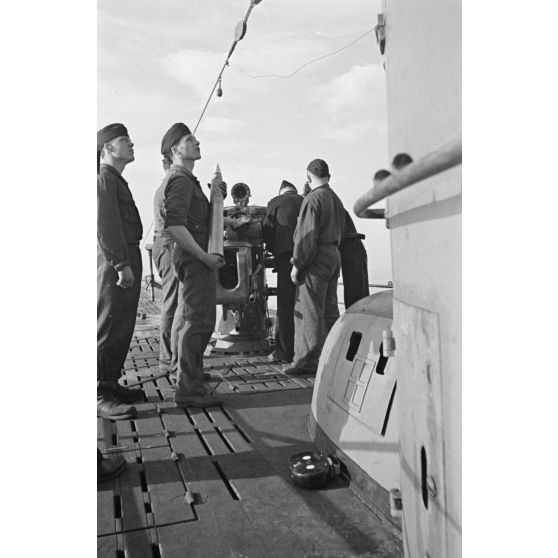 A bord d'un sous-marin allemand (U-boot), les sous-mariniers s'exercent au canon de 10,5 cm SK C/32 (Schnellladekanone - canon à chargement rapide).