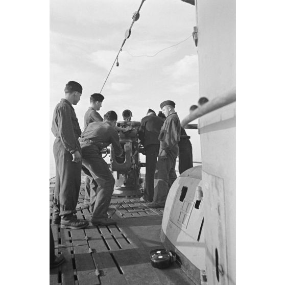 A bord d'un sous-marin allemand (U-boot), les sous-mariniers s'exercent au canon de 10,5 cm SK C/32 (Schnellladekanone - canon à chargement rapide).