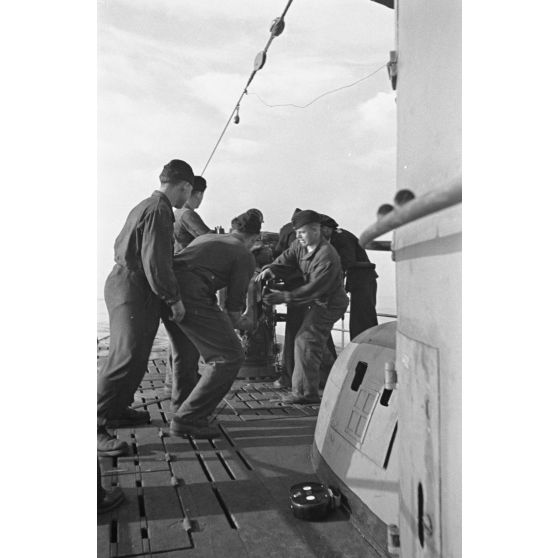 A bord d'un sous-marin allemand (U-boot), les sous-mariniers s'exercent au canon de 10,5 cm SK C/32 (Schnellladekanone - canon à chargement rapide).