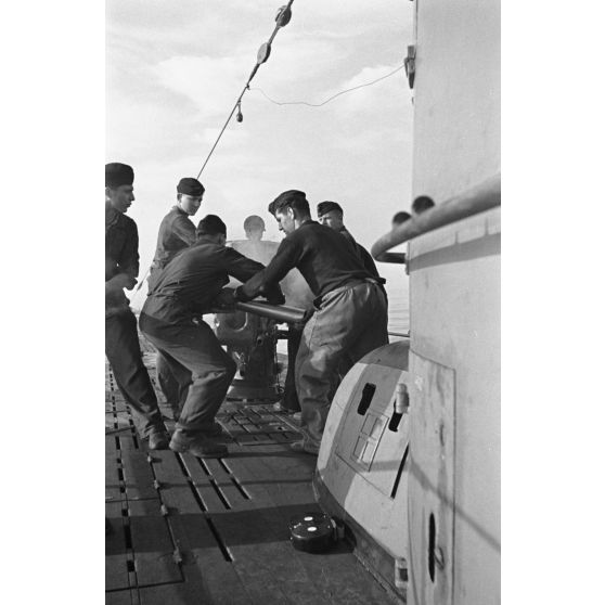 A bord d'un sous-marin allemand (U-boot), les sous-mariniers s'exercent au canon de 10,5 cm SK C/32 (Schnellladekanone - canon à chargement rapide).