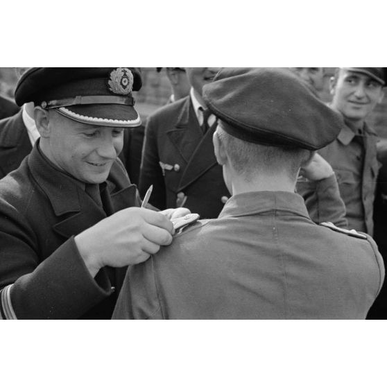 Sur le quai du port de Saint-Nazaire, un officier, membre de l'équipage d'un U-boot, reçoit les pattes d'épaule d'Oberleutnant zur See suite à une promotion.