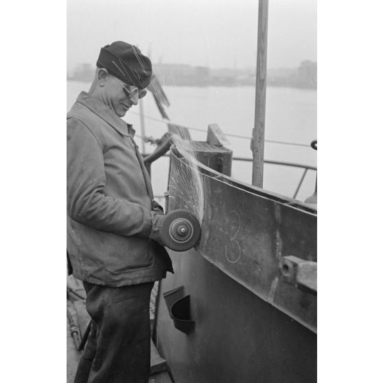 Portrait d'un marin effectuant une réparation sur un sous-marin allemand U-boot, l'ouvrier se focalise sur le kiosque du submersible.