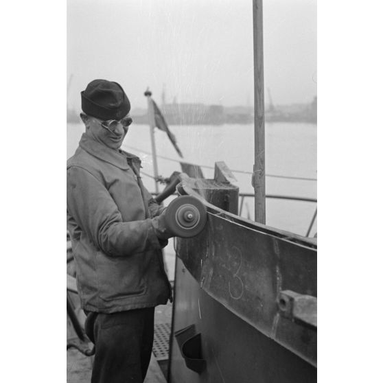 Portrait d'un marin effectuant une réparation sur un sous-marin allemand U-boot, l'ouvrier se focalise sur le kiosque du submersible.