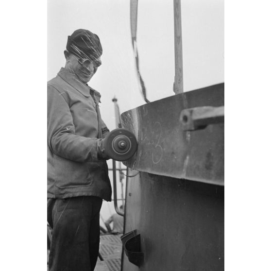 Portrait d'un marin effectuant une réparation sur un sous-marin allemand U-boot, l'ouvrier se focalise sur le kiosque du submersible.