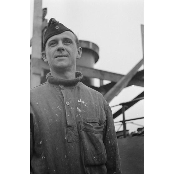 Portrait d'un marin effectuant une réparation sur un sous-marin allemand U-boot, l'ouvrier se focalise sur le kiosque du submersible.