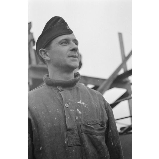 Portrait d'un marin effectuant une réparation sur un sous-marin allemand U-boot, l'ouvrier se focalise sur le kiosque du submersible.