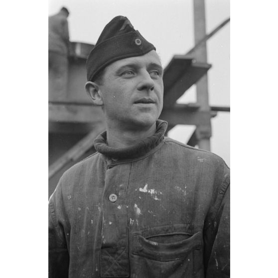 Portrait d'un marin effectuant une réparation sur un sous-marin allemand U-boot, l'ouvrier se focalise sur le kiosque du submersible.