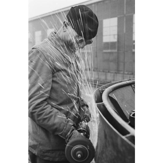 Portrait d'un marin effectuant une réparation sur un sous-marin allemand U-boot, l'ouvrier se focalise sur le kiosque du submersible.