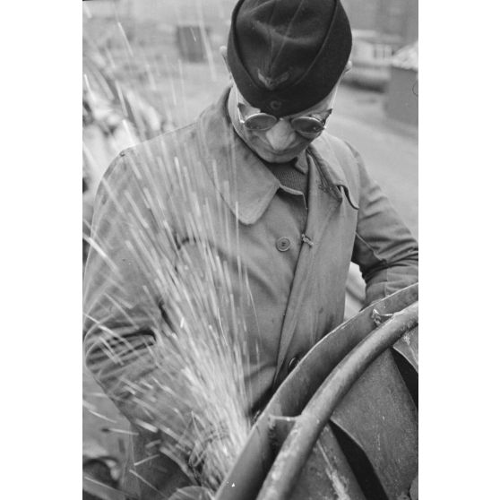 Portrait d'un marin effectuant une réparation sur un sous-marin allemand U-boot, l'ouvrier se focalise sur le kiosque du submersible.