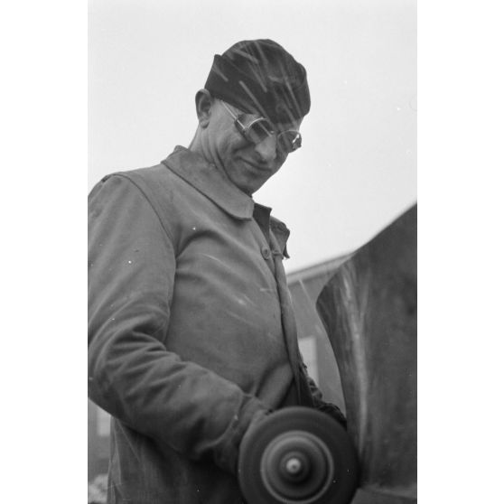Portrait d'un marin effectuant une réparation sur un sous-marin allemand U-boot, l'ouvrier se focalise sur le kiosque du submersible.