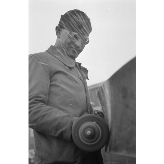 Portrait d'un marin effectuant une réparation sur un sous-marin allemand U-boot, l'ouvrier se focalise sur le kiosque du submersible.
