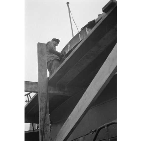 Portrait d'un marin effectuant une réparation sur un sous-marin allemand U-boot, l'ouvrier se focalise sur le kiosque du submersible.