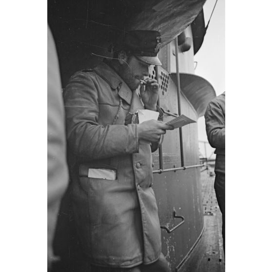A Saint-Nazaire, sur le pont d'un sous-marin peu après son retour de croisière, un sous-officier découvre son courrier en fumant une cigarette.