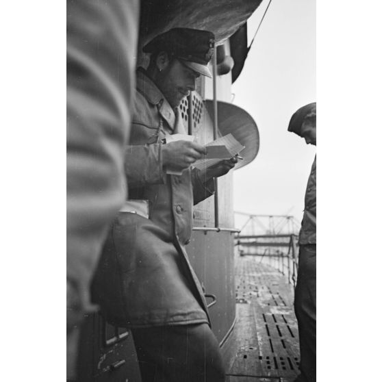 A Saint-Nazaire, sur le pont d'un sous-marin peu après son retour de croisière, un sous-officier découvre son courrier en fumant une cigarette.