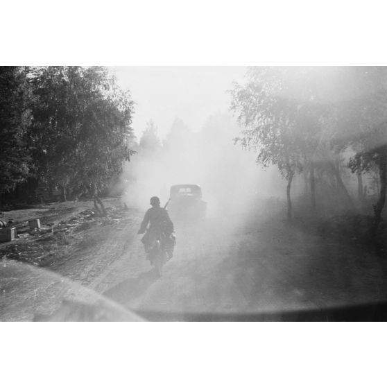 Progression de véhicules dans la poussière et le contre-jour.