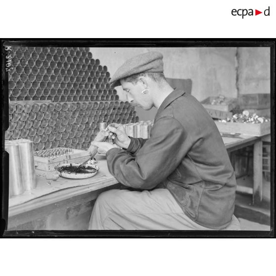 St Ouen. Usine Ruggieri. Confection des cartouches éclairantes pour fusils. Mise en place de l'allumeur. [légende d'origine]