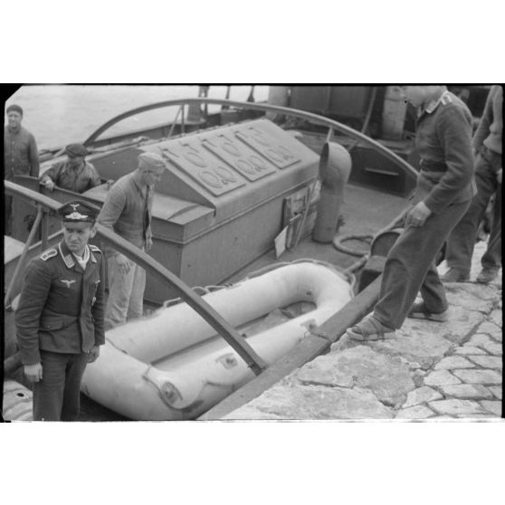 Sur le quai d'un port de la baie de Souda, un canot de sauvetage est déchargé par des personnels de la Luftwaffe.