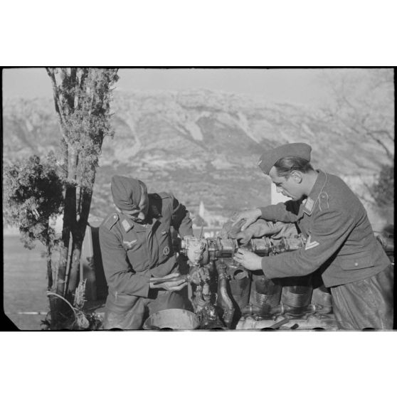 Deux aviateurs de la Luftwaffe travaillent sur un moteur, à gauche le caporal-chef est titulaire du brevet de démineur de la Kriegsmarine.