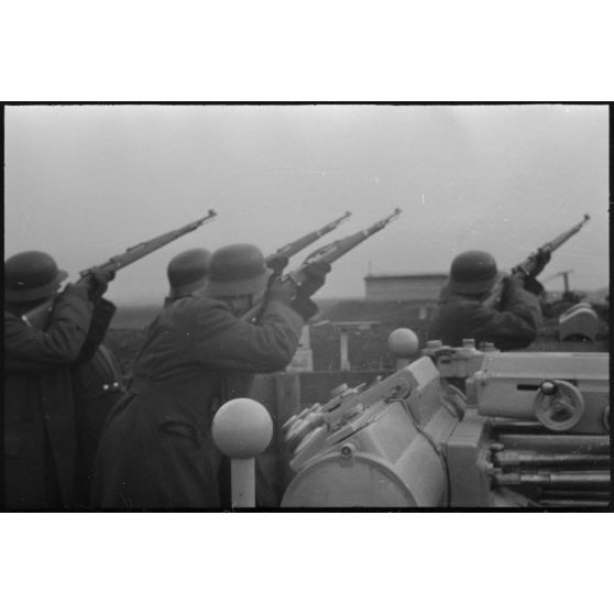 Au sein d'une batterie de 8,8 cm FlaK, les servants d'un télémètre (Kommandogerät 36) apportent leur appui feu à l'aide de fusil Mauser 98k.