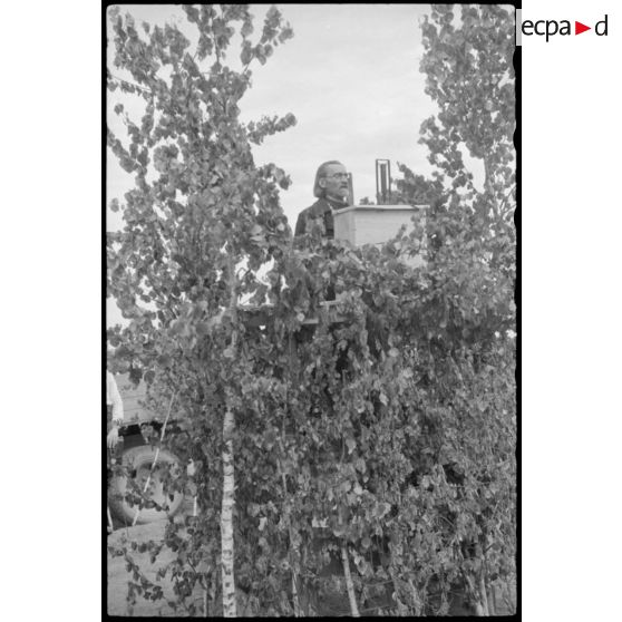 Un pope prononce un discours à une tribune, peu avant le défilé des volontaires sous l'uniforme allemand.