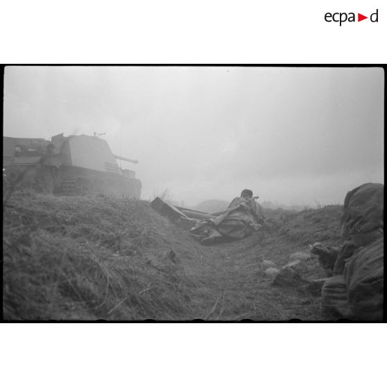 Un Nashorn du schwere Panzer Abteilung 519 tire, des fantassins restent en contre-bas.