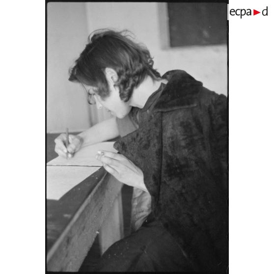 Portrait d'une femme répondant à des questions et rédigeant un courrier, il pourrait s'agir d'un interrogatoire.