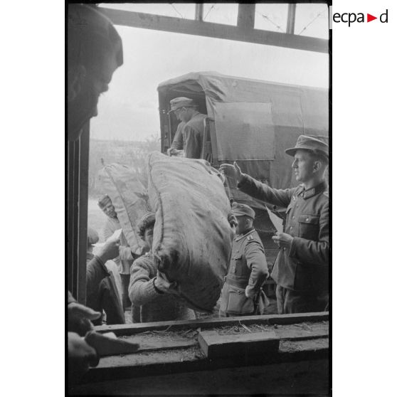 Déchargement de camions par des soldats allemands et des civils requis.
