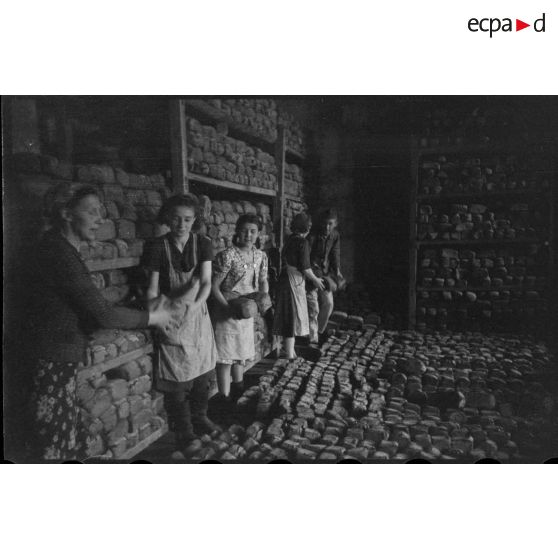 Des femmes et un soldat allemand assemblent des montagnes de pain.