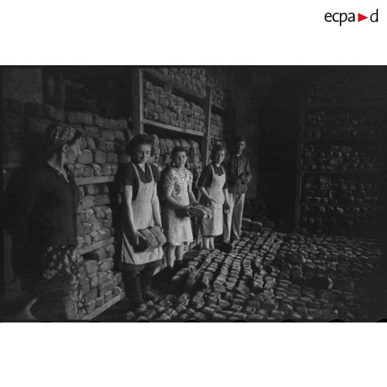 Des femmes et un soldat allemand assemblent des montagnes de pain.