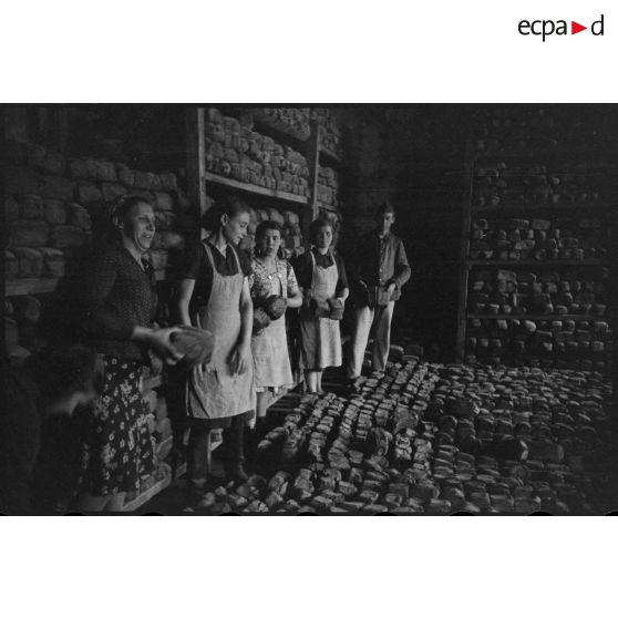 Des femmes et un soldat allemand assemblent des montagnes de pain.