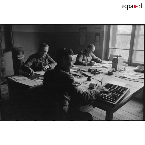 A l'intérieur de bureaux, des militaires et des civils s'occupent de la comptabilité du magasin d'approvisionnement.