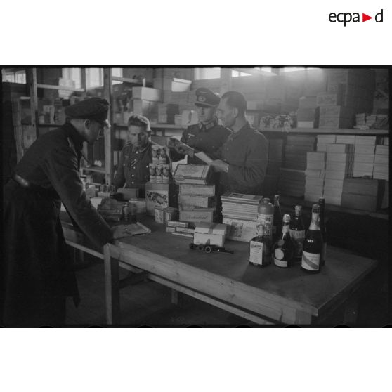 Un officier récupère sa commande, les vivres sont rassemblés sur une table et contrôlées par le personnel du magasin.