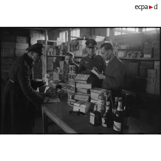 Un officier récupère sa commande, les vivres sont rassemblés sur une table et contrôlées par le personnel du magasin.
