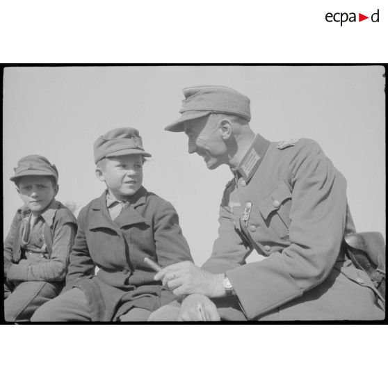 Un lieutenant-colonel (Oberstleutnant) échange avec des jeunes habitants d'un village.