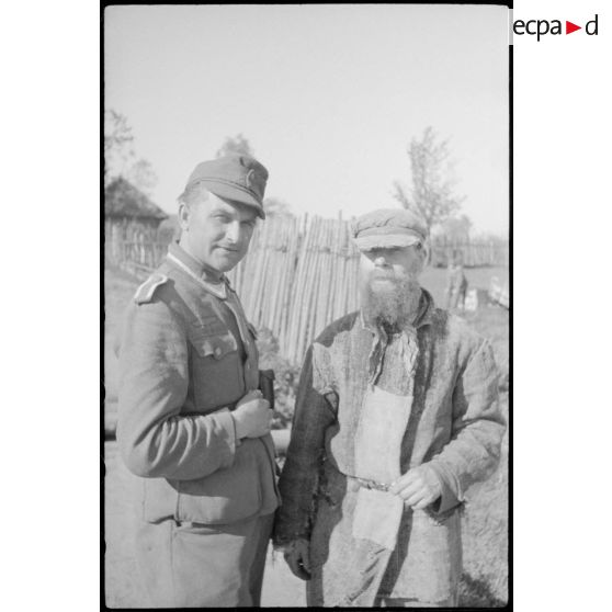 Un sous-officier de la Panzer Propagandakompanie 697 en compagnie d'un homme âgé.