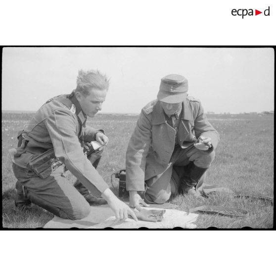 Un lieutenant-colonel (Oberstleutnant) et un capitaine se concentre devant une carte, un téléphone de campagne est à proximité.