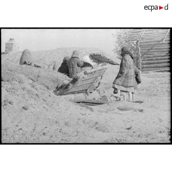 En raison des combats qui se déroulent à proximité, une femme et des enfants se tiennent à proximité d'un abri creusé dans le sol.