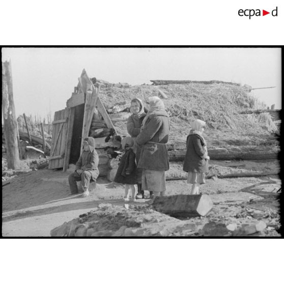 En raison des combats qui se déroulent à proximité, une femme et des enfants se tiennent à proximité d'un abri creusé dans le sol.