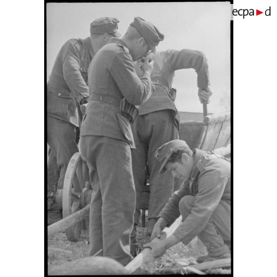 Des fantassins allemandes réparent une charrette qui transportera leurs effets personnels.