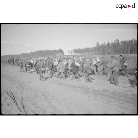 Prisonniers ou villageois requis avancent sous la garde de fantassins allemands.