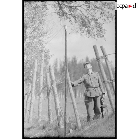 Un soldat allemand s'interroge devant le câble d'une ligne téléphonique.
