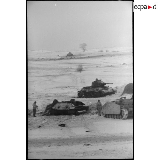 Un équipage d'un canon d'assaut examine deux carcasses de chars soviétiques T-34.