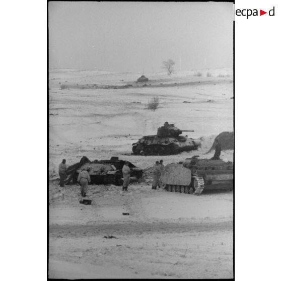 Un équipage d'un canon d'assaut examine deux carcasses de chars soviétiques T-34.