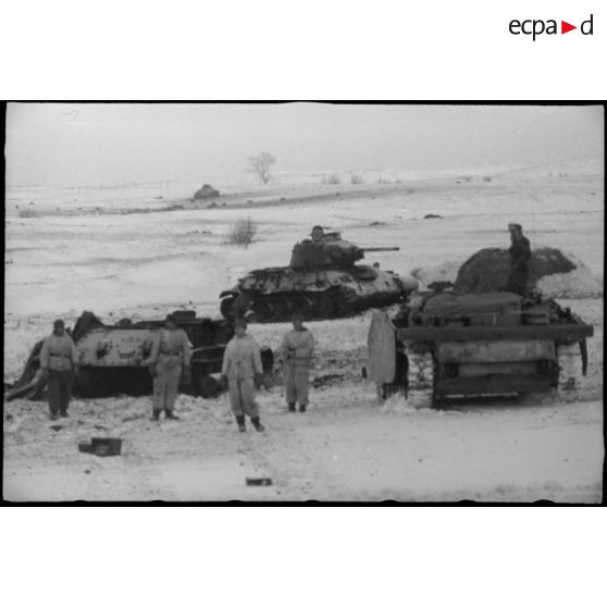 Un équipage d'un canon d'assaut examine deux carcasses de chars soviétiques T-34.