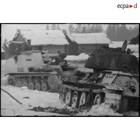 Un Sd.kfz.124 "Wespe" passe devant un char soviétique T-34 détruit.